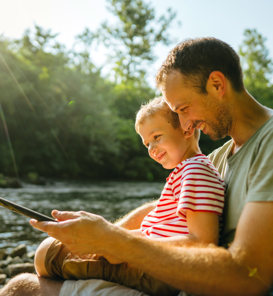 A dad fishing with young child in his lap.