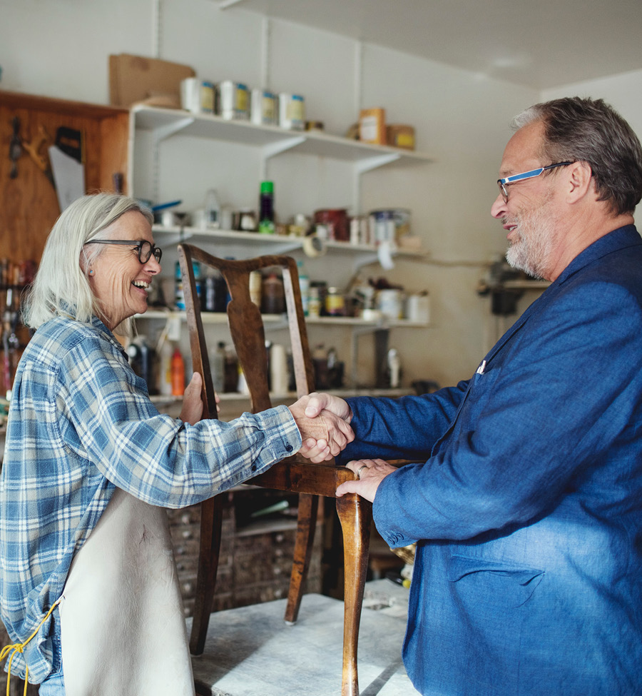 Woman shakes hands with man buying restored furniture.