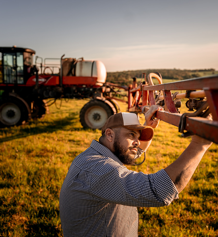 A man surveys a piece of farm equipment in a field.