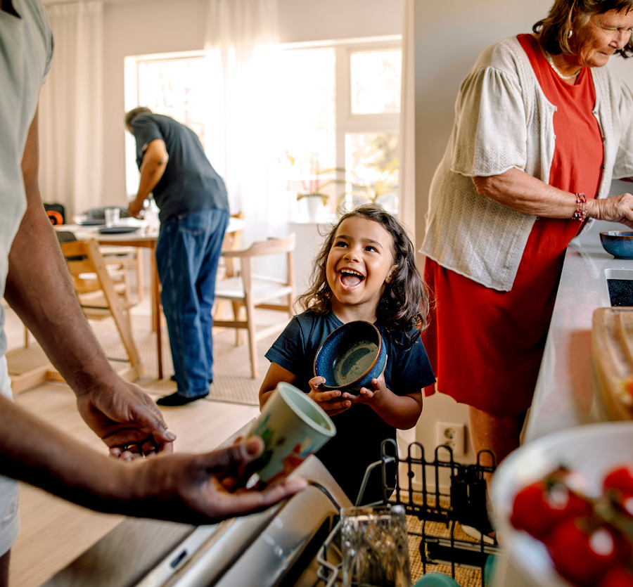 A multigenerational family unloading the dishwasher together.