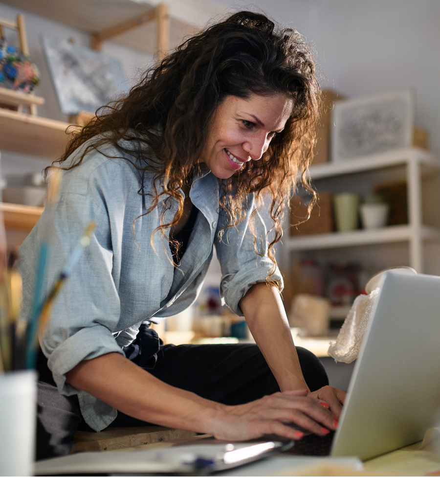 Business woman smiles while working on her laptop at her place of business. 