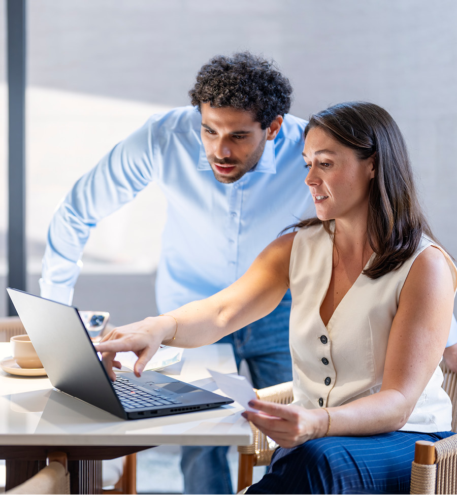 A man looks over woman's shoulder as she points at something on the screen.