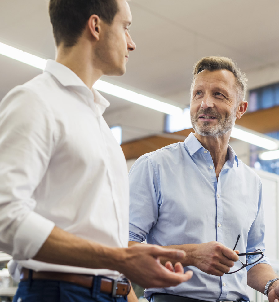 Two business men stand conversing together.