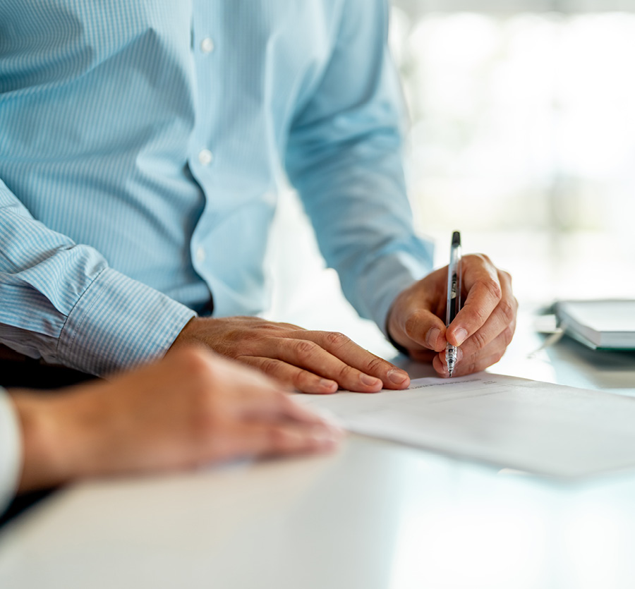 A man signs a piece of paper on a counter.
