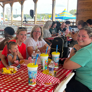 Family gathered around a picnic table at a community event having a good time.