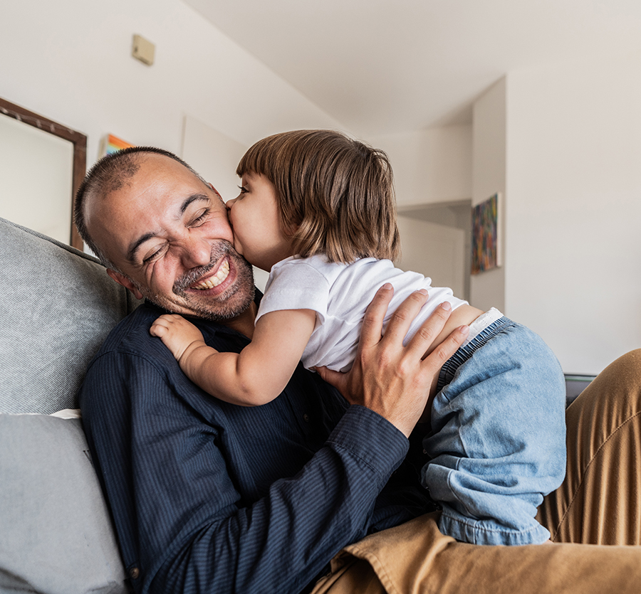 Dad and toddler playing on the couch in the living room.