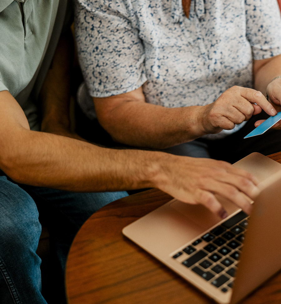 Couple holding card while sitting at computer