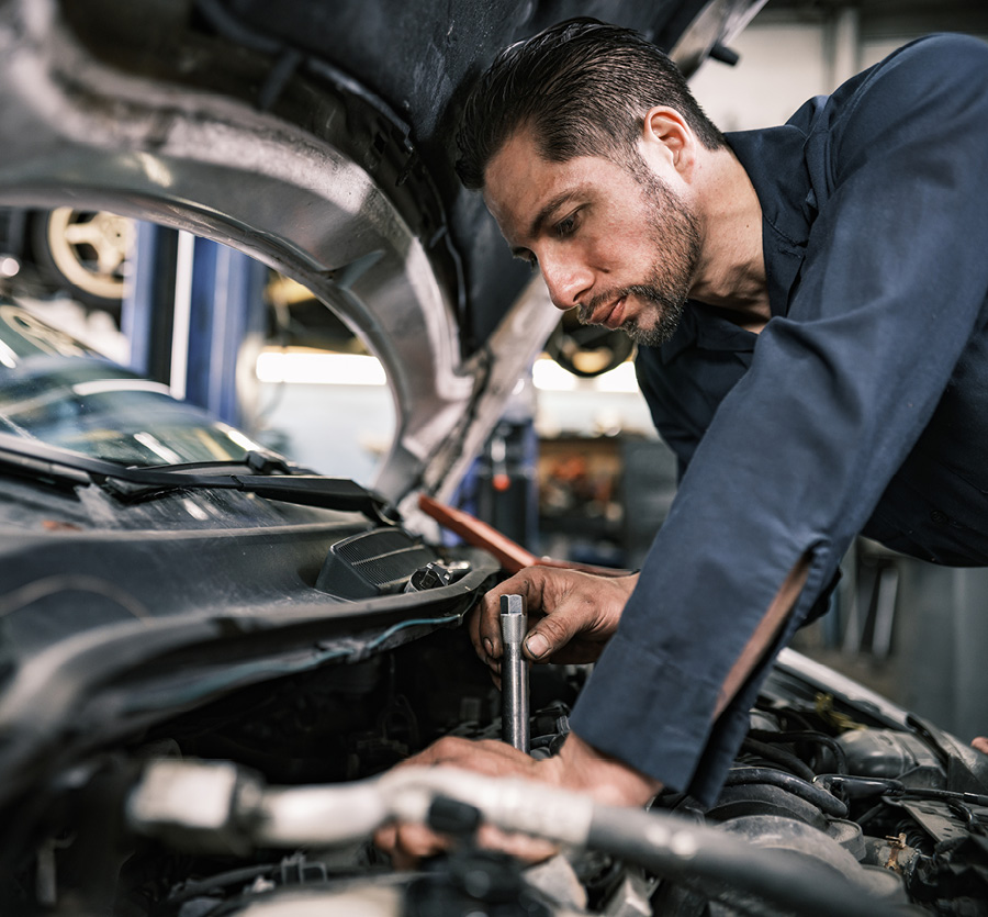 A man repairs a car engine under open hood.