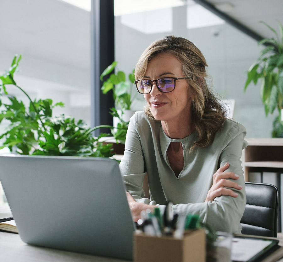 A woman smiles, looking at something on her computer screen.