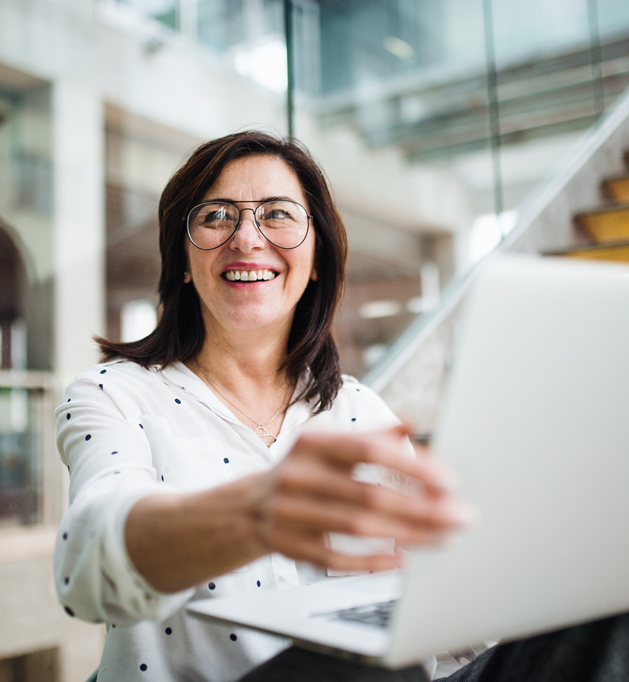 Women in front of a computer smiling, reaching to close it.