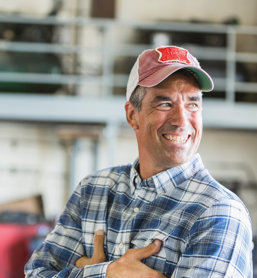 A man stands smiling, arms folded, looking to someone out of frame.
