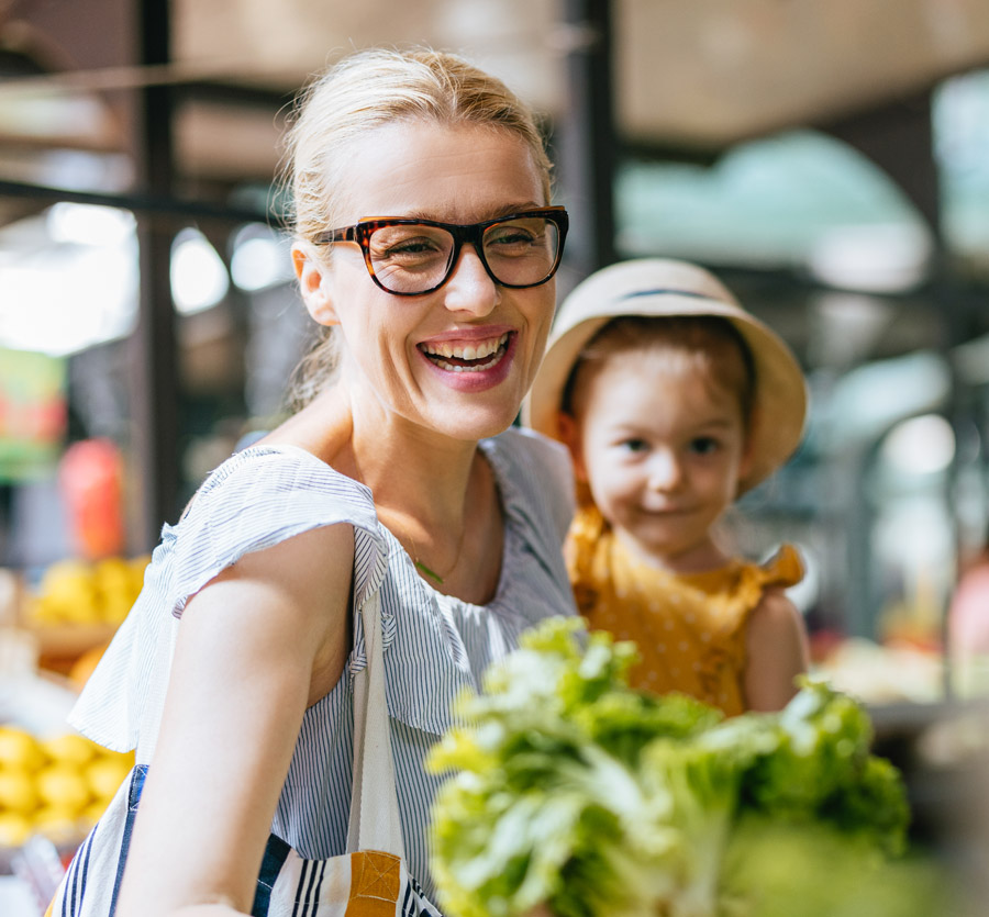 Young mother with daughter in hand at the market 