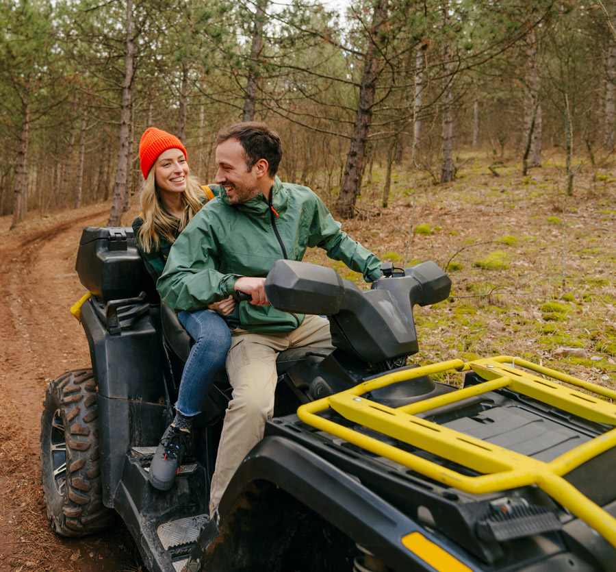 Couple riding a four wheeler in woods