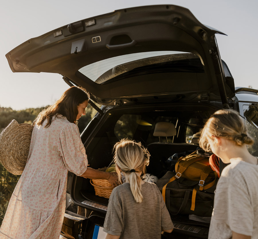Mother unpacking car for a picnic with daughters