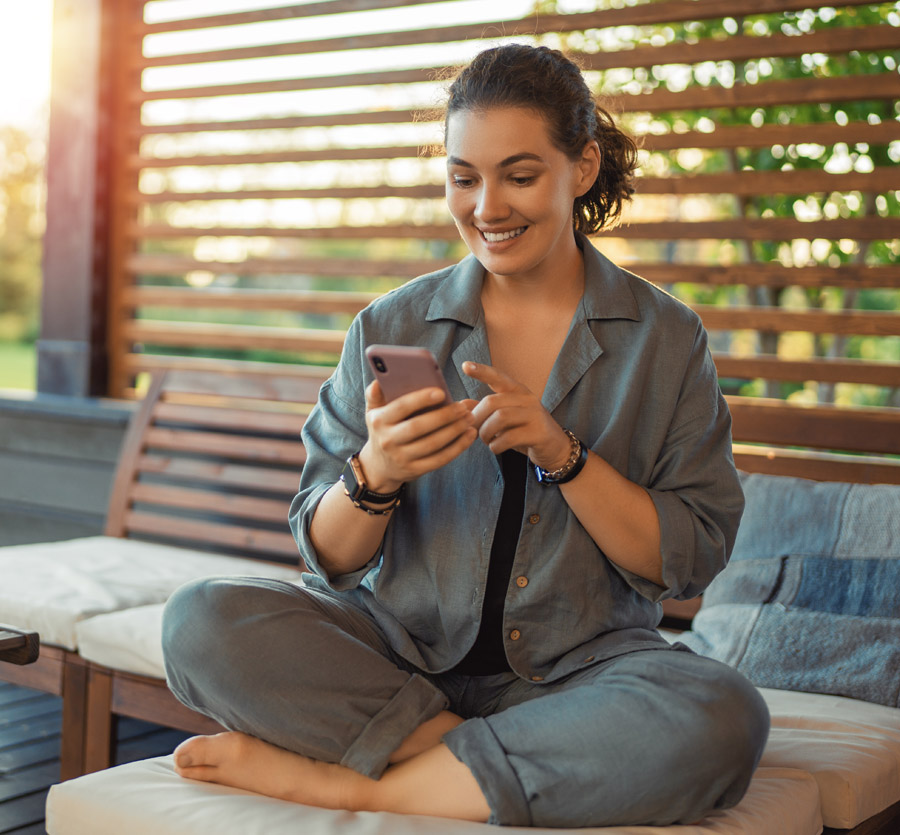 Woman holding mobile phone sitting outside