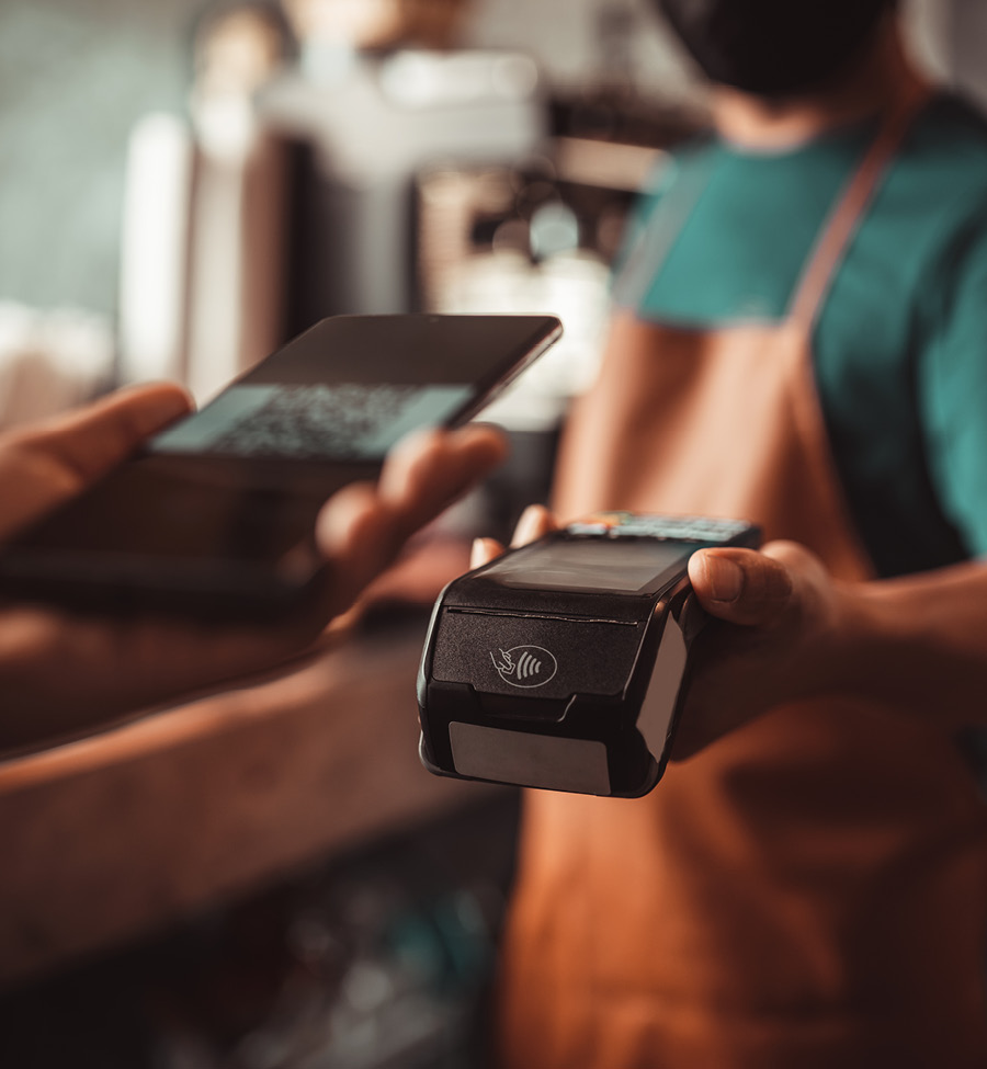 A man holds out card reader to customer using phone for tap-to-pay.