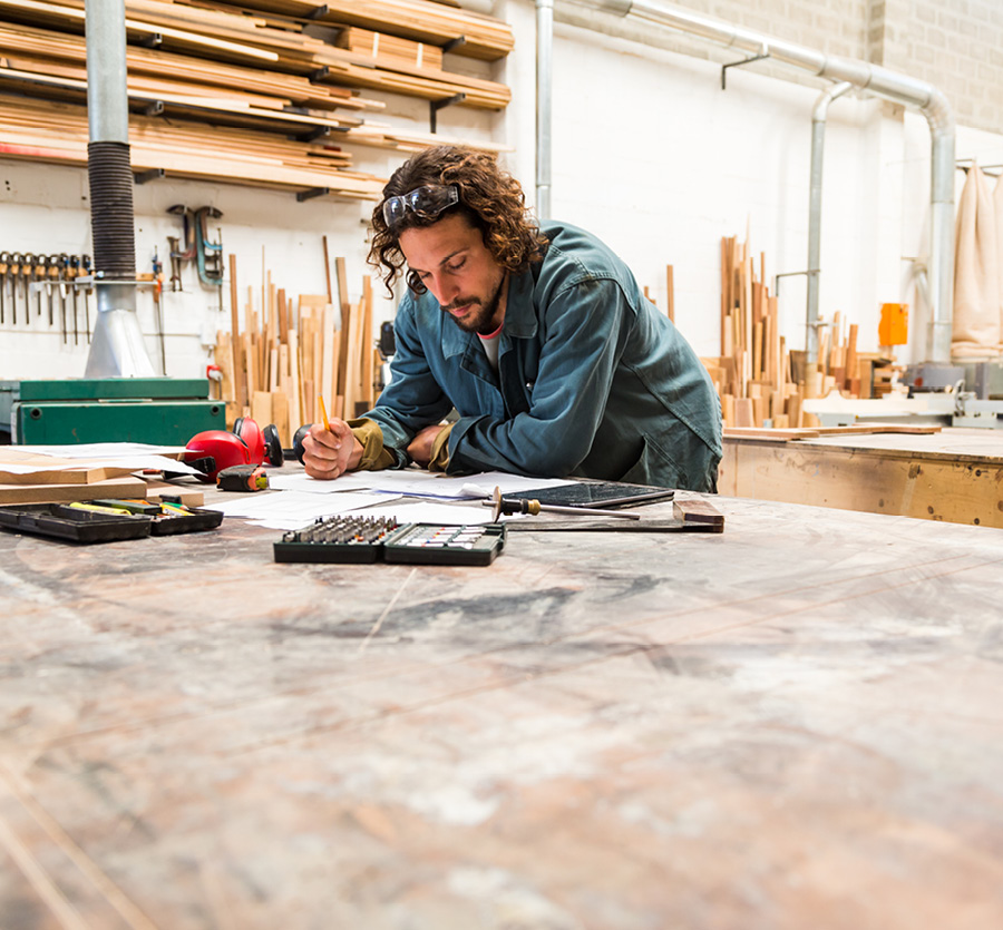 A man reviews plans on table in workshop.