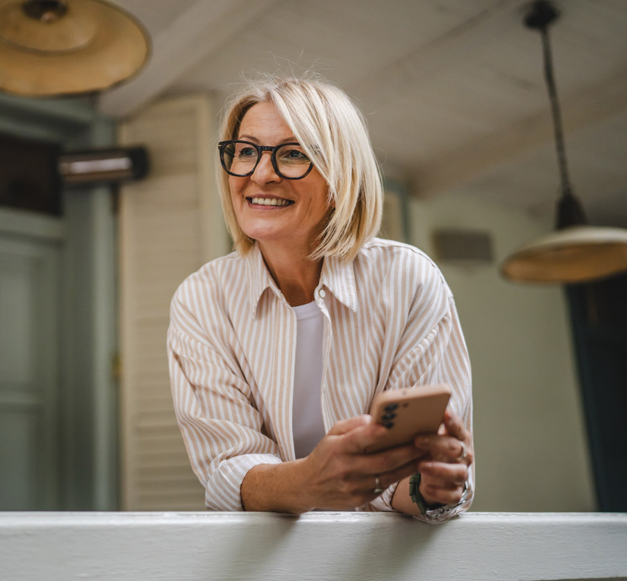Mature woman on porch with mobile phone in hand