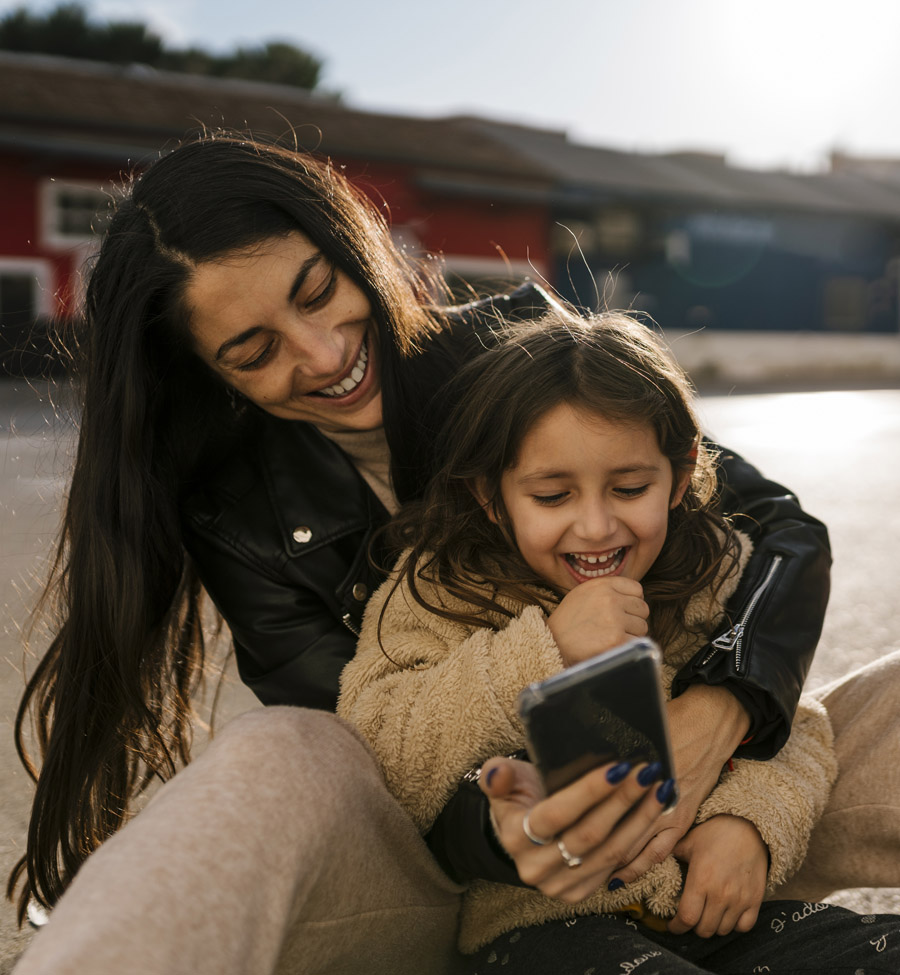 Mother holding child and phone laughing 