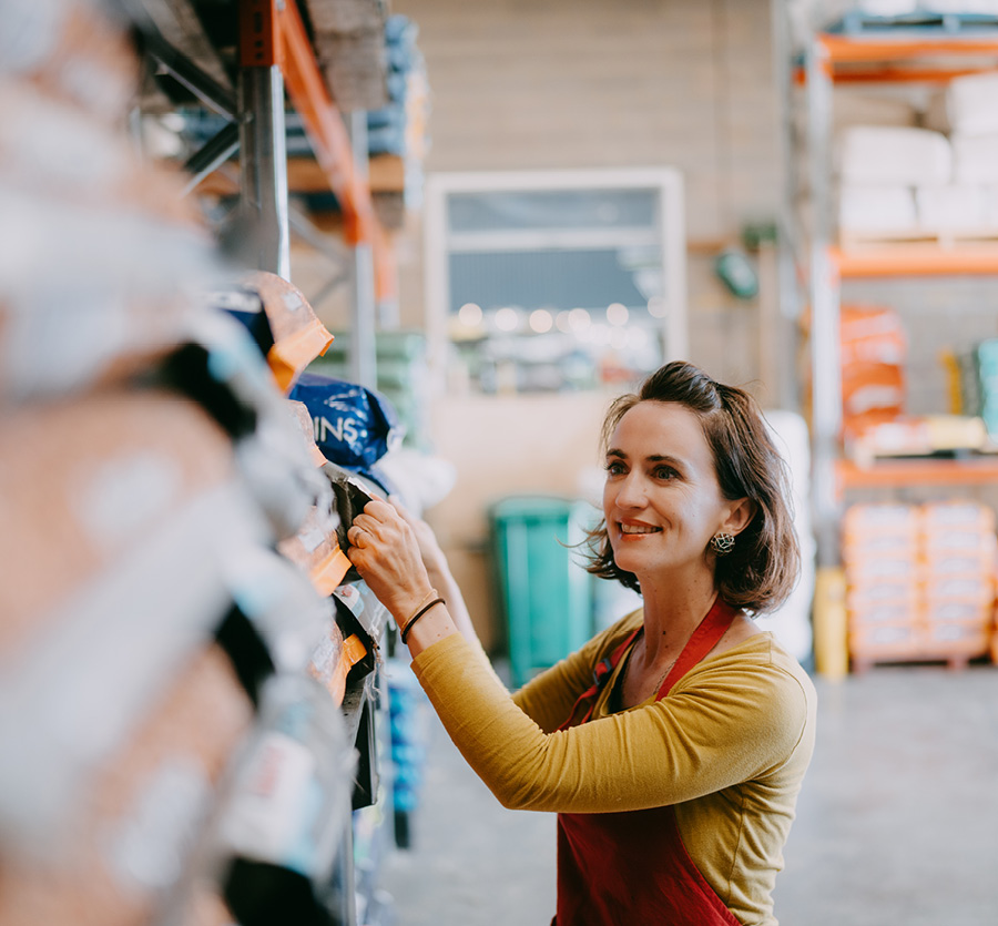 A woman reviews inventory on shelves in a warehouse.