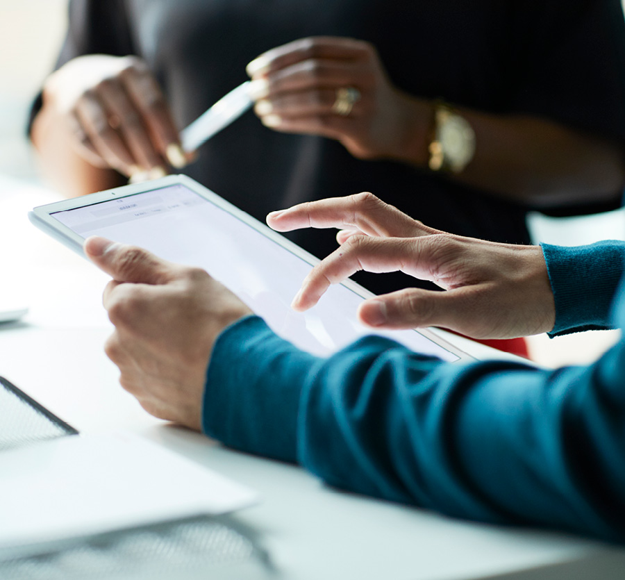 Person holds tablet in hand, scrolling during a meeting.